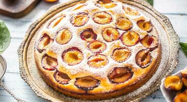 Homemade plum cake in vintage plate on wooden table. Plums pie with sugar powder photo