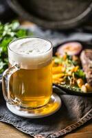 Glass of light beer in pub or restavurant on table with delicoius food photo