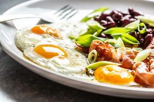 Inglés desayuno con huevos, tocino, frijoles y yo joven cebolla en blanco plato foto