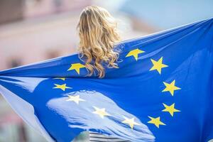 atractivo contento joven niña con el bandera de el europeo Unión foto