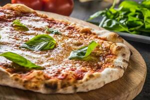 italiano tradicional Pizza margarita en redondo de madera tablero con albahaca Tomates y parmesano foto