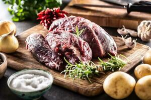 Raw meat in form of beef shank ready to be cooked with onions, herbs, spices, garlic and potatoes photo