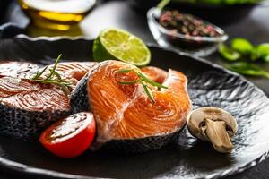 Salmon raw steaks rosemary tomatoes mushroom lime olive oil and spices. photo