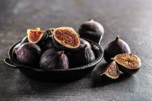 A few figs in a black bowl on an dark concrete table photo