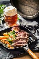 Beef flank steak in grill pan with batata puree garlic herb decoration and draft beer photo