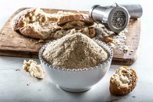 A white bowl full of breadcrumbs and old dry bread around photo