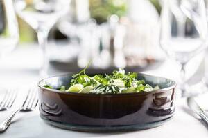 Side photo of a dark bowl filled with kohlrabi and spinach green salad