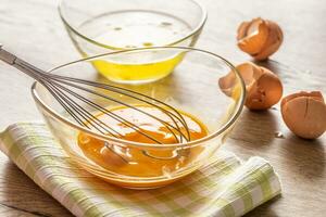 Whisked egg yolks in a glass bowl with egg whites in a second bowl and crackjed egg shells on the side photo