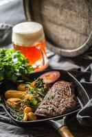 Beef flank steak in grill pan with batata puree garlic herb decoration and draft beer photo