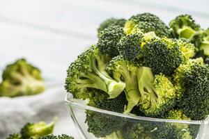 Fresh broccoli in bowl on wooden table photo