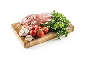 Pork neck raw meat with garlic parsley herbs tomatoes and rosemary on butcher board isolated on white background photo