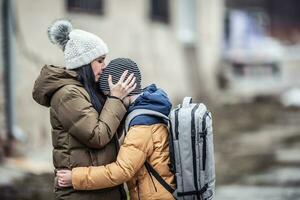 Vysne Nemecke, Slovakia. March 09. 2022. Woman kisses her boy on forehead outdoors as they both stay in the war zone after Russia attacked Ukraine photo