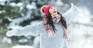 atrapando copos de nieve a abierto boca al aire libre por un contento mujer en suéter, bufandas y un invierno sombrero foto