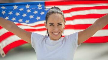 Smiling young attractive female holding American flag behind her back photo