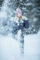 joven mujer en calentar ropa es teniendo divertido fuera de el nieve foto