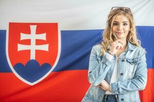 Pretty girl with thinking gesture stands in front of the flag of Slovak republic photo