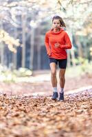 joven hembra atleta en ropa de deporte carreras en el parque durante calentar indio verano foto