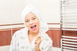 Teenage girl in bathroom with toothbrush. Morning and evening dental hygiene photo