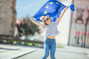 atractivo contento joven niña con el bandera de el europeo Unión foto