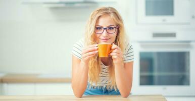 taza de café en mano de contento joven mujer. atractivo niña Bebiendo Mañana té foto