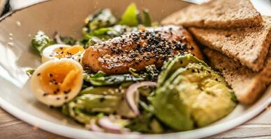 Grilled salmon with sezame is put on fresh leaf salad photo