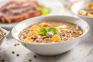 Lentil soup with pieces of smoked pork neck, carrots, potatoes and coriander photo