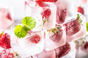 Fresh strawberries frozen in ice blocks with melissa leaves photo