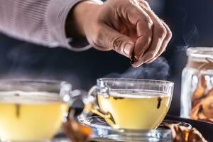 Detail of a bartender's hand flavoring hot mulled wine with cloves photo