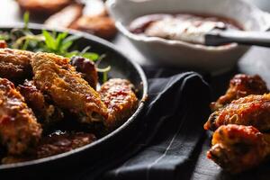 Chicken wings barbeque in a cast iron baking dish with BBQ sauce and rosemary photo