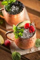 Moscow Berry Mule highball vodka cocktail is a long drink with fresh lime juice, ginger beer and berries photo