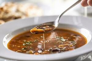 detalle de un cuchara de Minestrone sopa encima el lleno plato foto