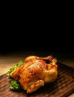 Roasted whole chicken on wooden cutting board photo