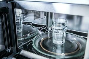 Inside view of new clean staniless, microwave oven with a cup of pure water photo