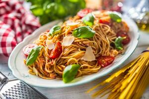 Italian pasta spaghetti bolognese in white bowl with tomatoes parmesan cheese and basil photo
