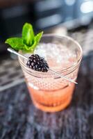 Cocktail drink bramble with black berries and mint at barcounter in night club or restaurant photo