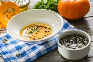 Pumpkin cream soup with seeds and parsley on kitchen table photo