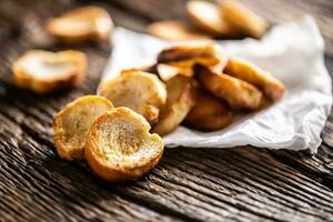 Freshly baked crispy bake rolls with goldish colour served in the paper on a rustic wooden desk photo