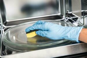 Woman hand cleaning microwave oven with sponge photo