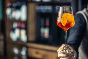 aperol rociar beber. barman mano participación vaso con aperol rociar bebida foto