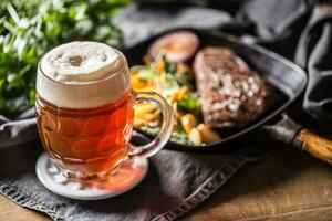 Glass of red beer in pub or restavurant on table with delicoius food photo