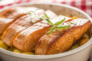 Baked salmon fillets with potatoes and herbs in a baking dish photo