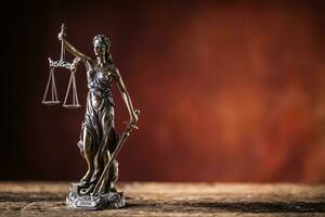 Lady Justicia holding sword and scale bronze figurine on wooden table photo