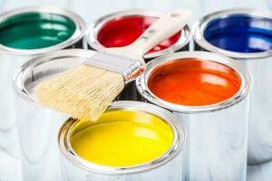 Close-up brush lying on multicolored paint cans. photo