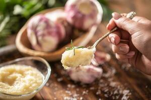 Detail of a teaspoon of garlic paste with fresh garlic in the background photo