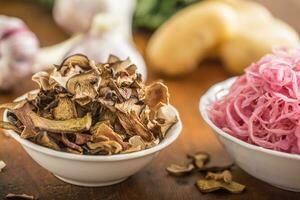 Sour cabbage and dried mushrooms in bowl on wooden table photo