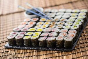 colección de Sushi maki en pizarra tablero con soja salsa y palillos foto