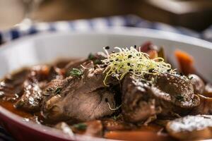 Roast wild boar with carrot mushrooms, baguette and draft beer photo