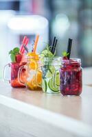 Various lemonades in mason jars with orange lime lemon otange strawberries and fresh fruit fruits photo