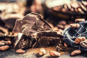 oscuro chokolate cacao frijoles y polvo en hormigón mesa foto
