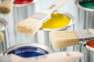 Close-up brushes lying on multicolored paint cans. photo